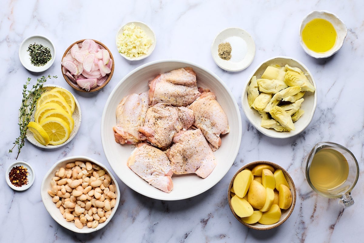 ingredients in bowls to make oven-roasted chicken with potatoes, white beans, and artichokes.