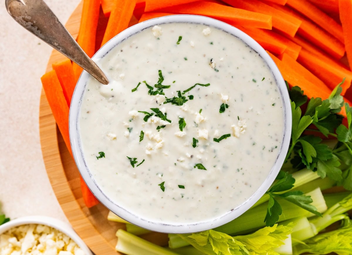blue cheese dip in bowl on tray with cut up vegetables.