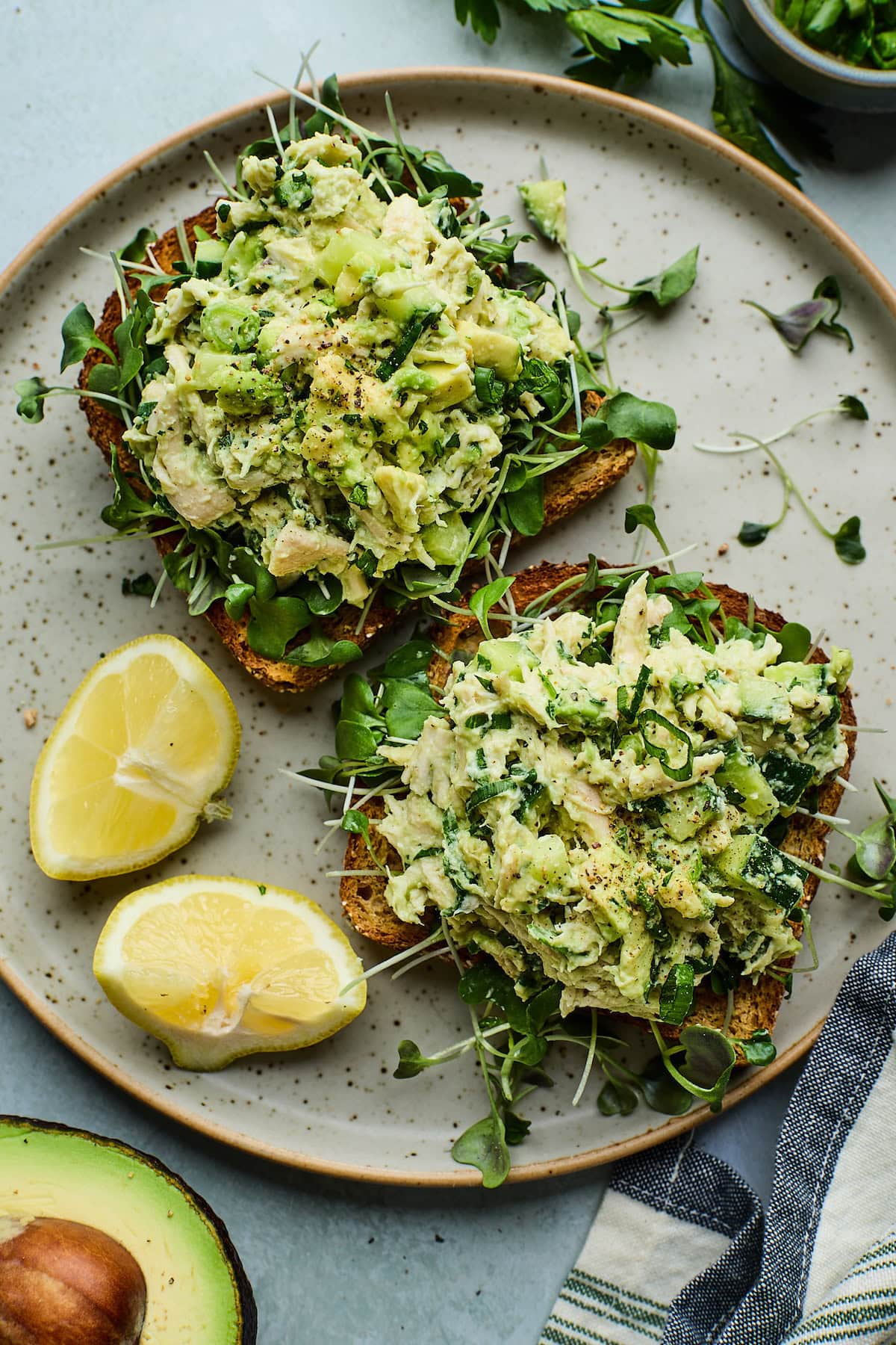 avocado chicken salad on toast with microgreens with fresh lemon wedges.