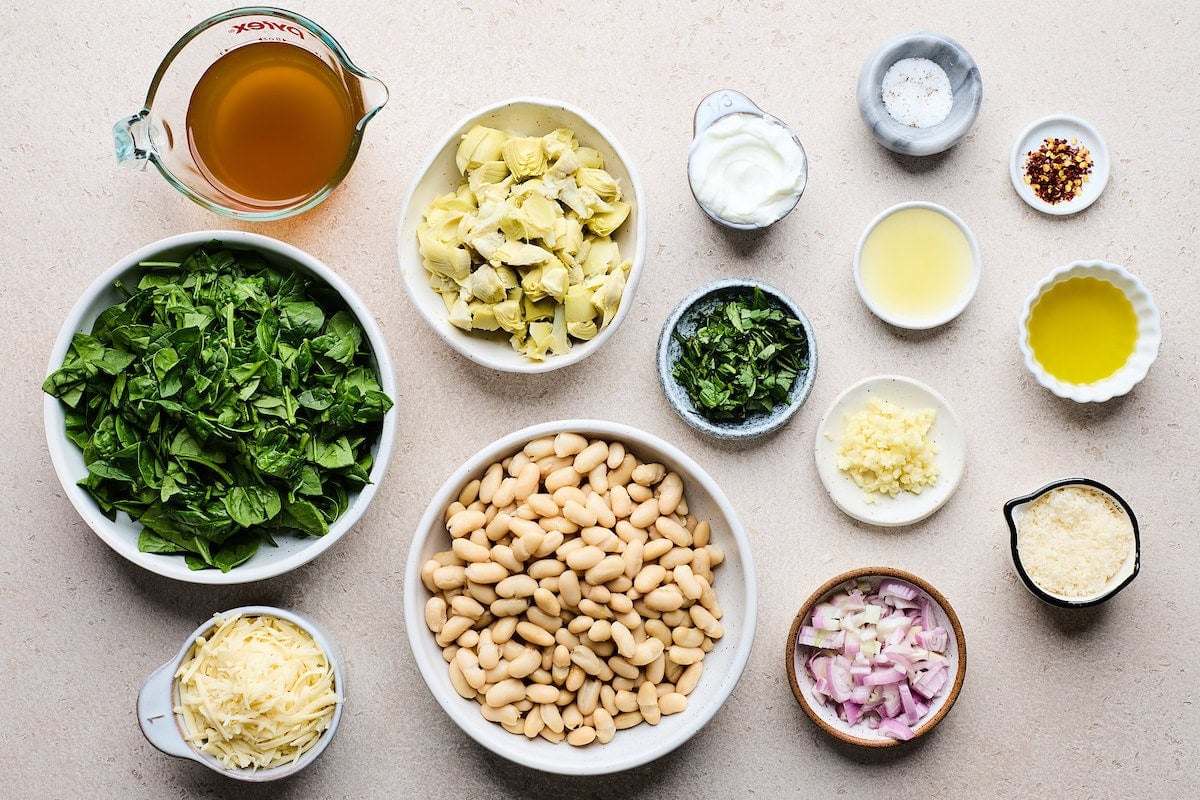 ingredients in bowls to make spinach artichoke white bean skillet.