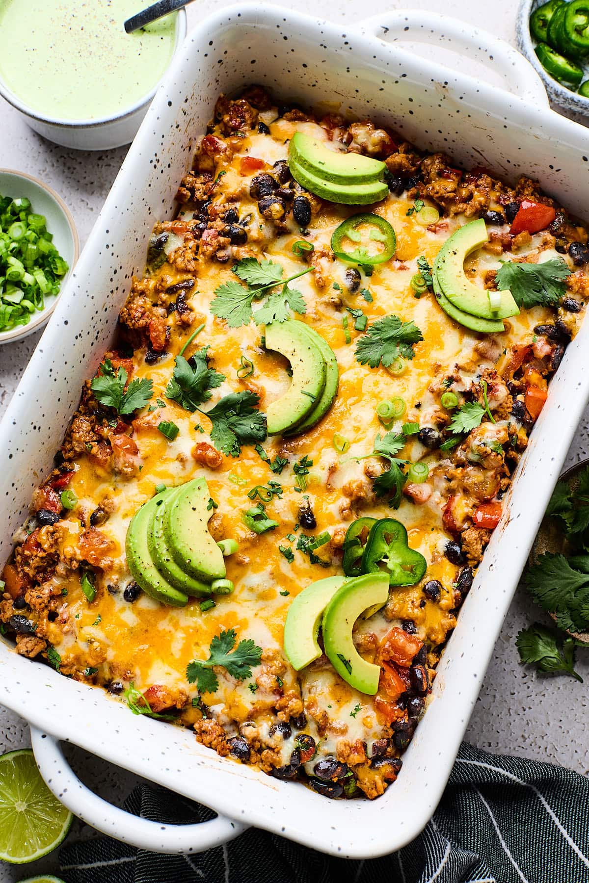 Sweet Potato Turkey Black Bean Bake in pan with avocado slices, cilantro, and jalapeño slices.